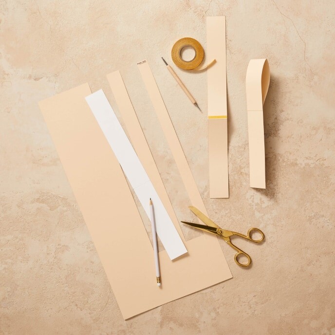 Stap 3: Een afbeelding van kartonnen papier met het sjabloon voor de handgrepen van de paasmand, voorgevouwen op de markeringen.